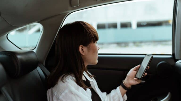 Passenger using a smartphone while riding in the back seat of a car