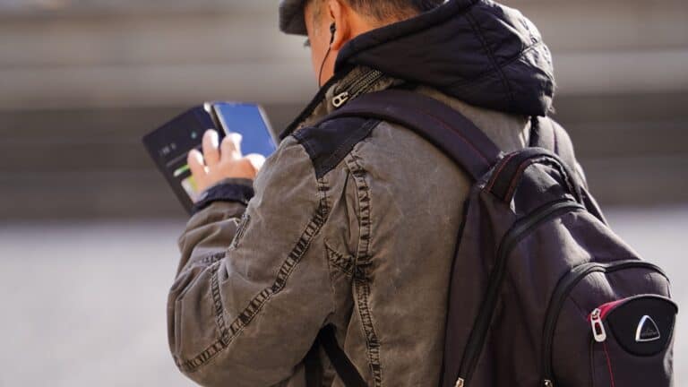 Traveler with a backpack using a smartphone for city navigation