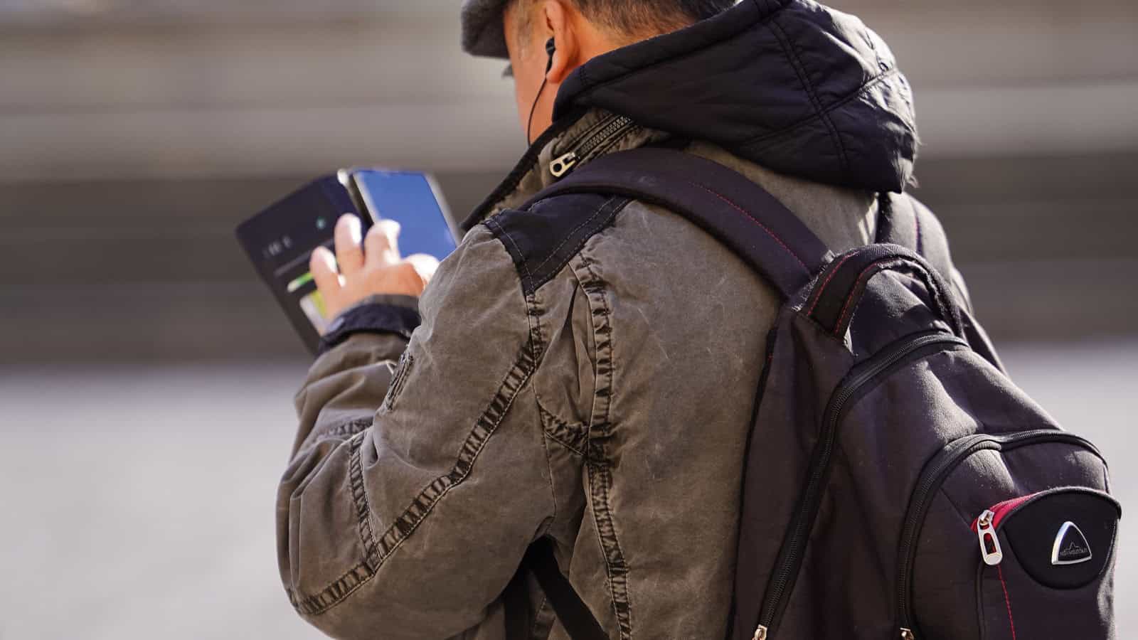Traveler with a backpack using a smartphone for city navigation